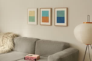 Tre indrammede plakater med passepartout over en sofa