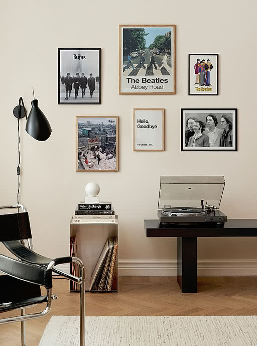 Gallery wall of Beatles posters above a record player in a styled interior — curated music prints that add atmosphere to bars, hotels and creative workspaces