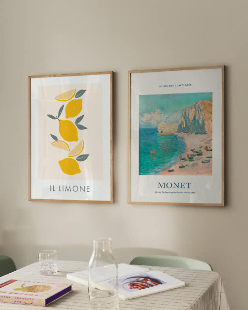 An Il Limone lemon print and a Monet Étretat beach print displayed above a grid-cloth dining table.