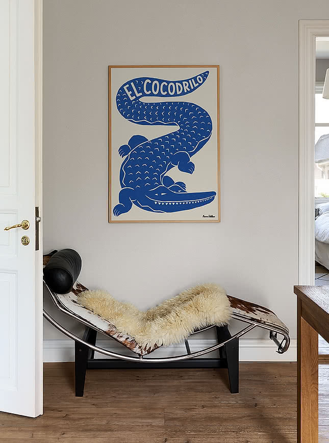 Affiche bleue El Cocodrilo dans un cadre en chêne au-dessus d'un fauteuil