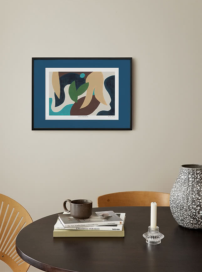 Affiche abstraite avec passe-partout bleu dans un cadre noir au-dessus d'une table ronde