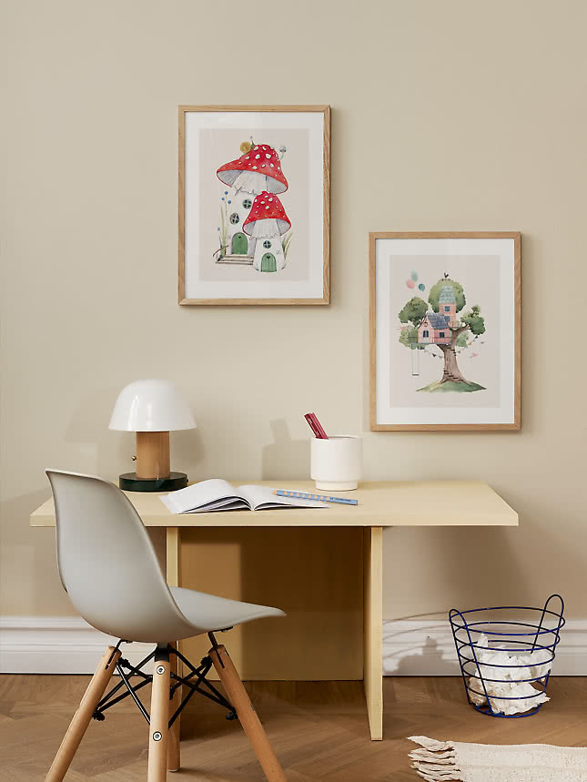 Deux affiches de maisons champignons au-dessus d'un bureau d'enfant avec une lampe