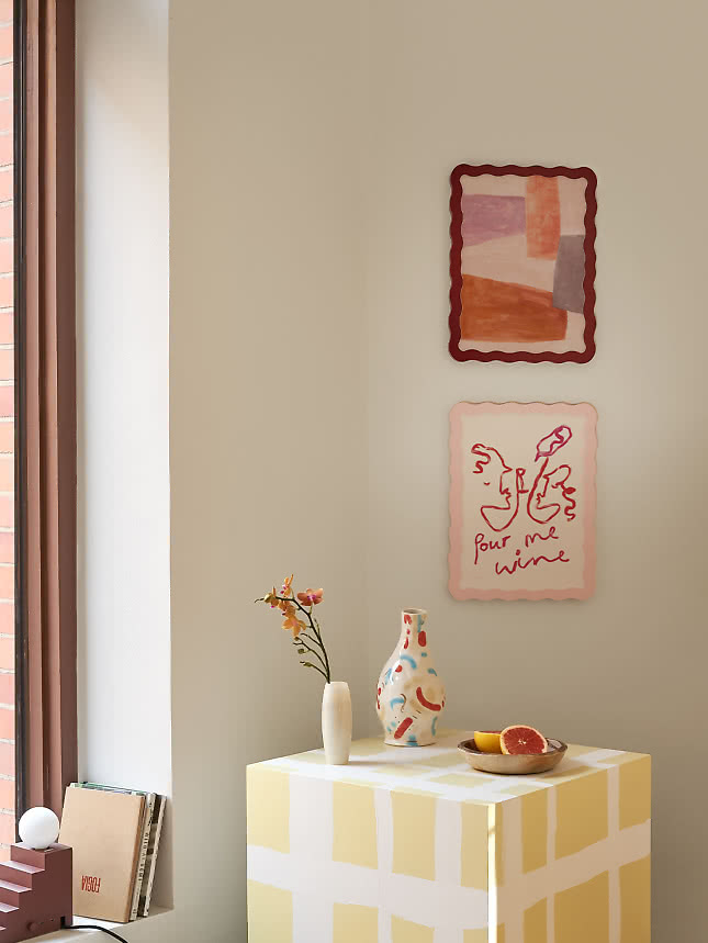 Twee art prints in Wavy Frame-lijsten boven een geel geruit bijzettafeltje