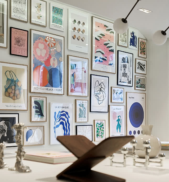 Large gallery wall of framed art prints in assorted styles in a showroom setting — a curated poster collection for retail and commercial display