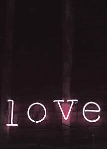 Insegna al neon rosa con la scritta "love" su una parete di legno scura