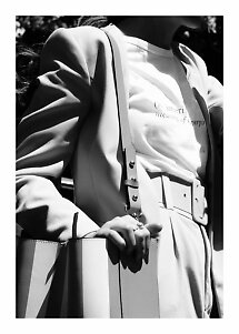 Black-and-white close-up of woman in blazer and T-shirt with wide belt, shoulder bag and large tote