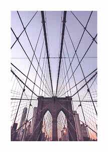 Udsigt op mod Brooklyn Bridge med krydsende kabler og bybygninger i solnedgang