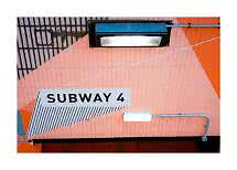 Panneau "SUBWAY 4" sur un mur carrelé rose et orange avec lampes et tuyaux apparents