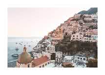Pastel-colored coastal town on a steep hillside with church dome and boats on the sea