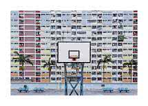Basketball hoop in front of a colorful apartment block with palm trees and benches