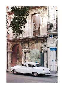 White vintage car parked in front of a weathered building with columns and balcony