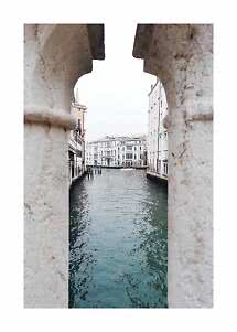 View of a Venetian canal between historic buildings, seen through a stone opening