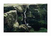 Stretta cascata in un profondo canyon coperto di muschio con ripide pareti rocciose