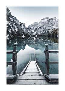 Wooden steps leading into a calm mountain lake with reflections of pale cliffs and forest