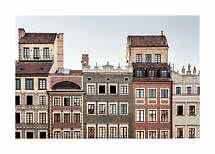 Reihe historischer Stadthäuser mit farbigen Fassaden und roten Ziegeldächern vor hellem Himmel