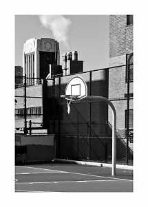 Black-and-white photo of an outdoor basketball hoop by a fence and buildings with steam behind