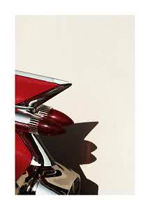 Close-up of a red vintage car tail fin with chrome and double tail lights against a light wall