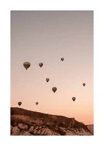 Mehrere Heißluftballons schweben über einer felsigen Landschaft im sanften Abendlicht