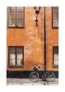 Schwarzes Fahrrad vor orangefarbener Putzfassade mit Fenstern und Wandleuchte