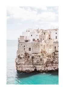 White and stone houses on a cliff above turquoise sea under a bright sky