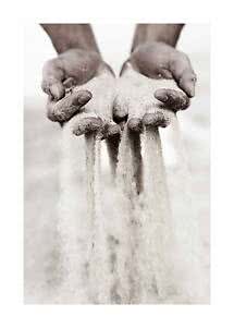 Hands holding fine sand as it pours down between the fingers