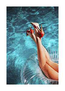 Legs on a clear pool float in blue water wearing red high-heeled pumps.