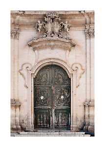 Portal barroco ornamentado de piedra clara con puertas dobles oscuras desgastadas y esculturas arriba