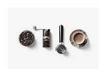 Skål med kaffebønner, håndkværn, portafilter og kop kaffe set ovenfra på hvid baggrund