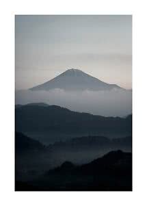 Kegelförmiger Berg über Wolken mit dunklen Bergsilhouetten im Vordergrund