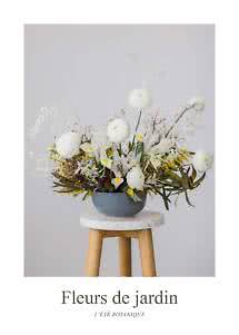 Blomsterarrangemang med vita blommor och gula detaljer i grå skål på en träpall