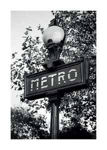Insegna Metro in bianco e nero su un palo con lampada e alberi sullo sfondo