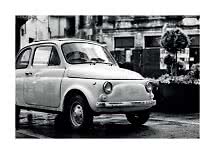 Black-and-white photo of a small vintage car parked on a wet street