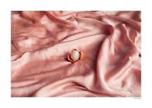Litchi ouvert sur un tissu rose satiné aux plis doux