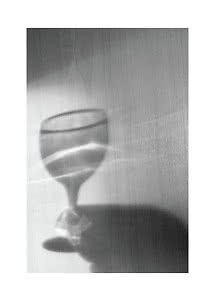 Verre sur pied avec eau et ombres douces sur une surface en bois clair