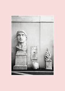 Foto in bianco e nero di sculture antiche in marmo contro un muro, con grande testa e mano
