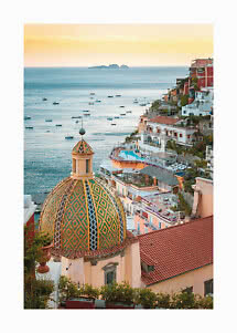 View of a coastal town with a colorful dome, boats on the sea, and golden sunset sky