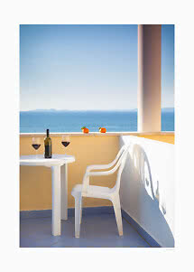 Sunny balcony with white chair and table, wine bottle, two glasses of red wine and sea view