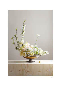 Elegant floral arrangement in a bronze bowl with white and cream roses on a light wooden table
