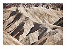 Colline desertiche beige ondulate con ombre profonde e formazioni rocciose stratificate