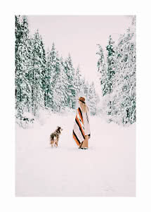 Femme en poncho rayé et chapeau avec un chien sur un chemin forestier enneigé