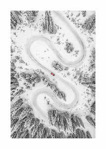Veduta aerea di strada innevata tortuosa nel bosco con una piccola auto rossa