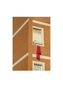 Red cloth hanging on a clothesline outside an orange building with white window frames