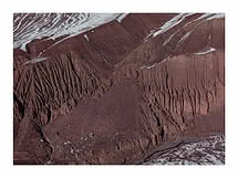 Rostroter Himalaya-Berghang mit feinen Erosionsrinnen und dünnen Schneestreifen entlang der Grate