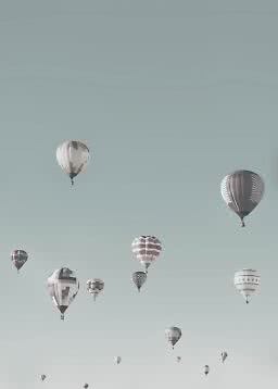 Mehrere Heißluftballons schweben am blassblauen Himmel