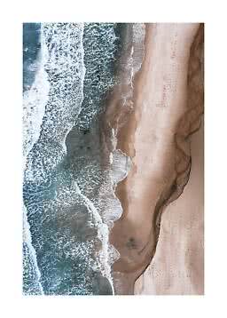 Aerial view of ocean waves washing onto a pale sandy beach