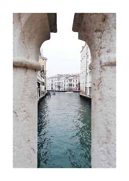 View of a Venetian canal between historic buildings, seen through a stone opening