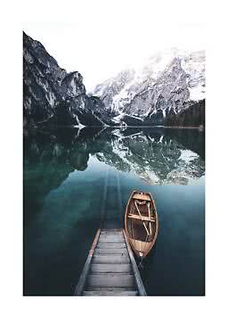 Wooden boat by a small dock on a calm mountain lake with reflected snowy peaks