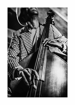 Gros plan en noir et blanc d’un musicien en veste à motifs jouant de la contrebasse