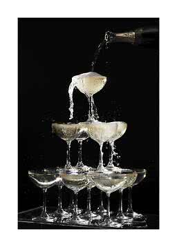 Champagne hældes i et tårn af coupeglas mod sort baggrund
