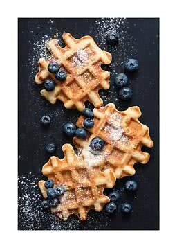 Tre waffle dorati con zucchero a velo e mirtilli su sfondo scuro